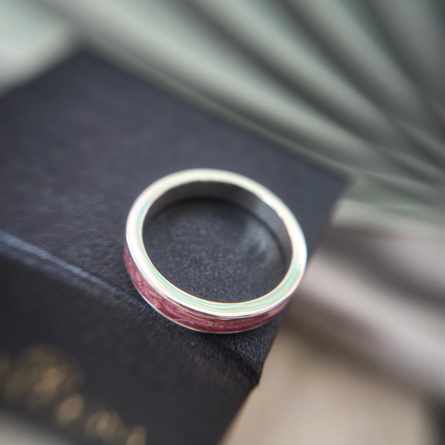 Silver ring with a red interior on a dark surface