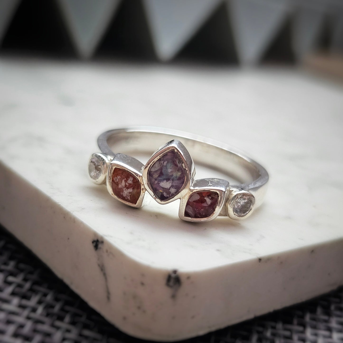 Silver ring with embedded gemstones on a textured surface