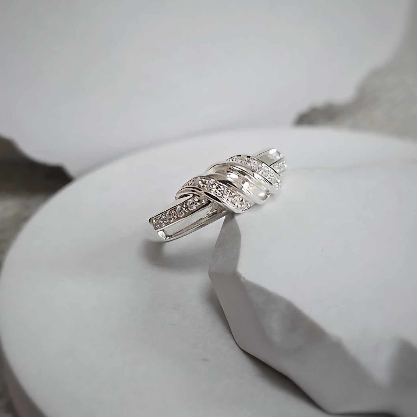 Silver ring with gemstones on a white stone surface