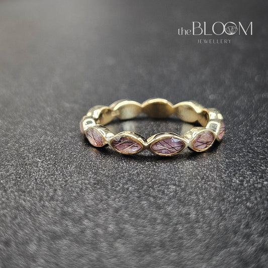 Gold ring with embedded stones on a dark textured surface, branded 'the BLOOM JEWELLERY'.