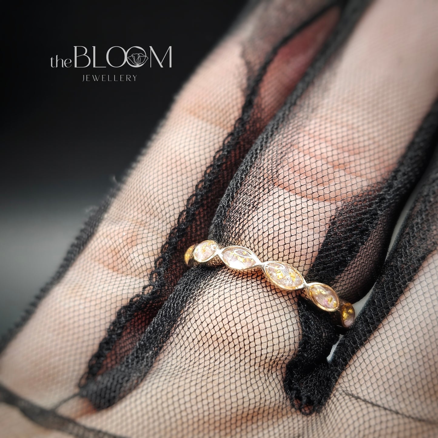 Gold ring on a hand wearing black mesh glove with 'the BLOOM JEWELLERY' branding.