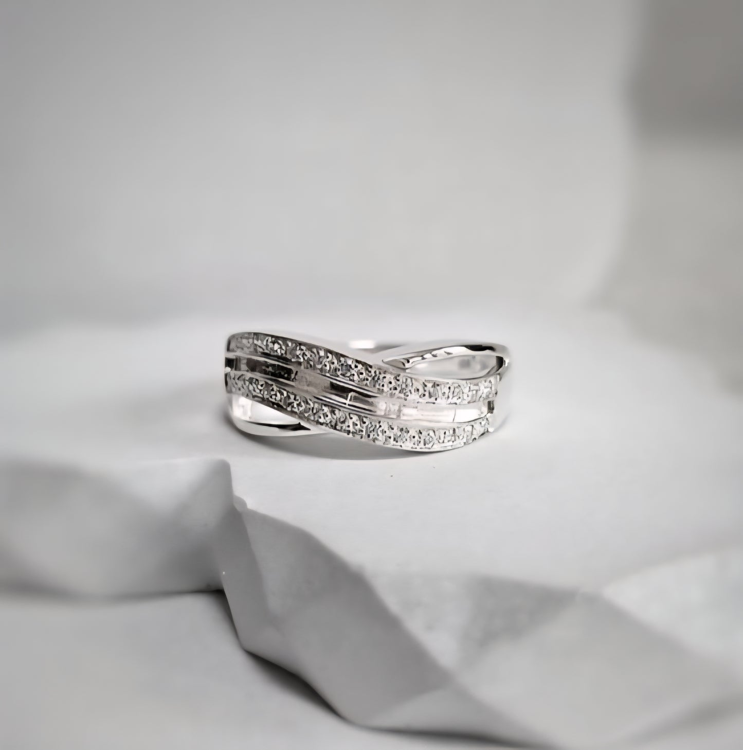 Silver ring with small diamonds on a light gray fabric background