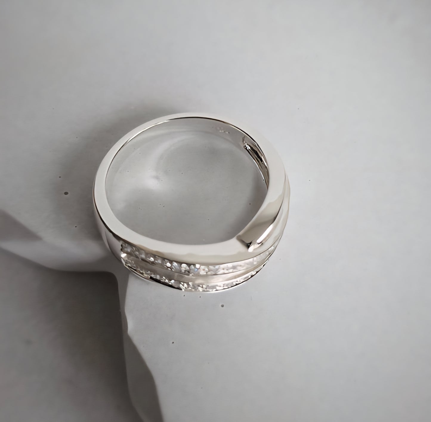 Silver ring with diamond accents on a light gray background
