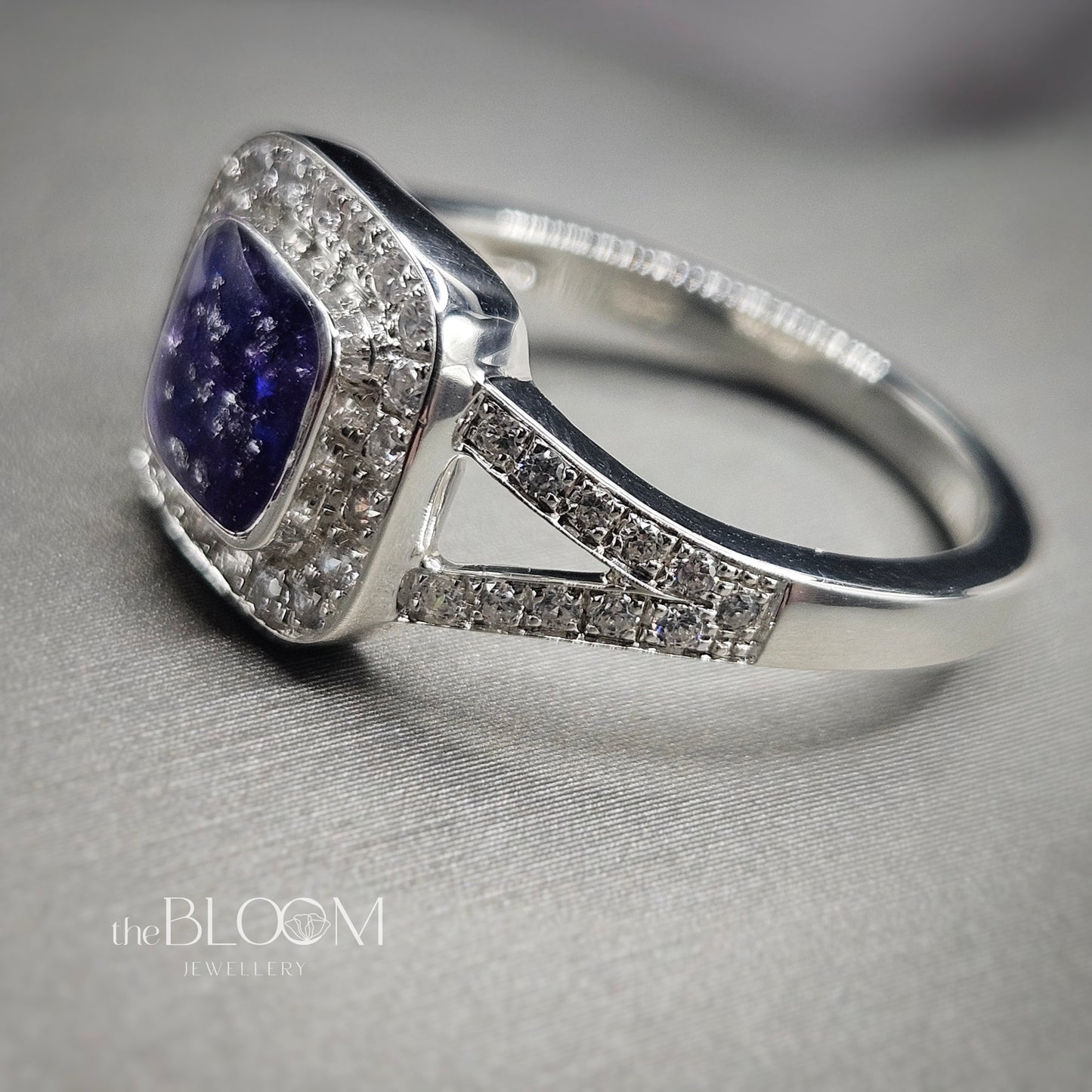 Silver ring with a purple gemstone on a gray background, branded 'the BLOOM JEWELRY'.