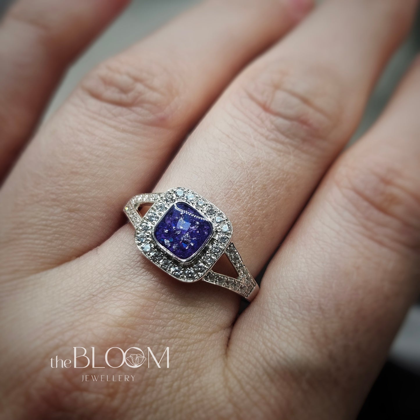 Ring with a purple gemstone on a finger, branded 'the BLOOM JEWELLERY'.