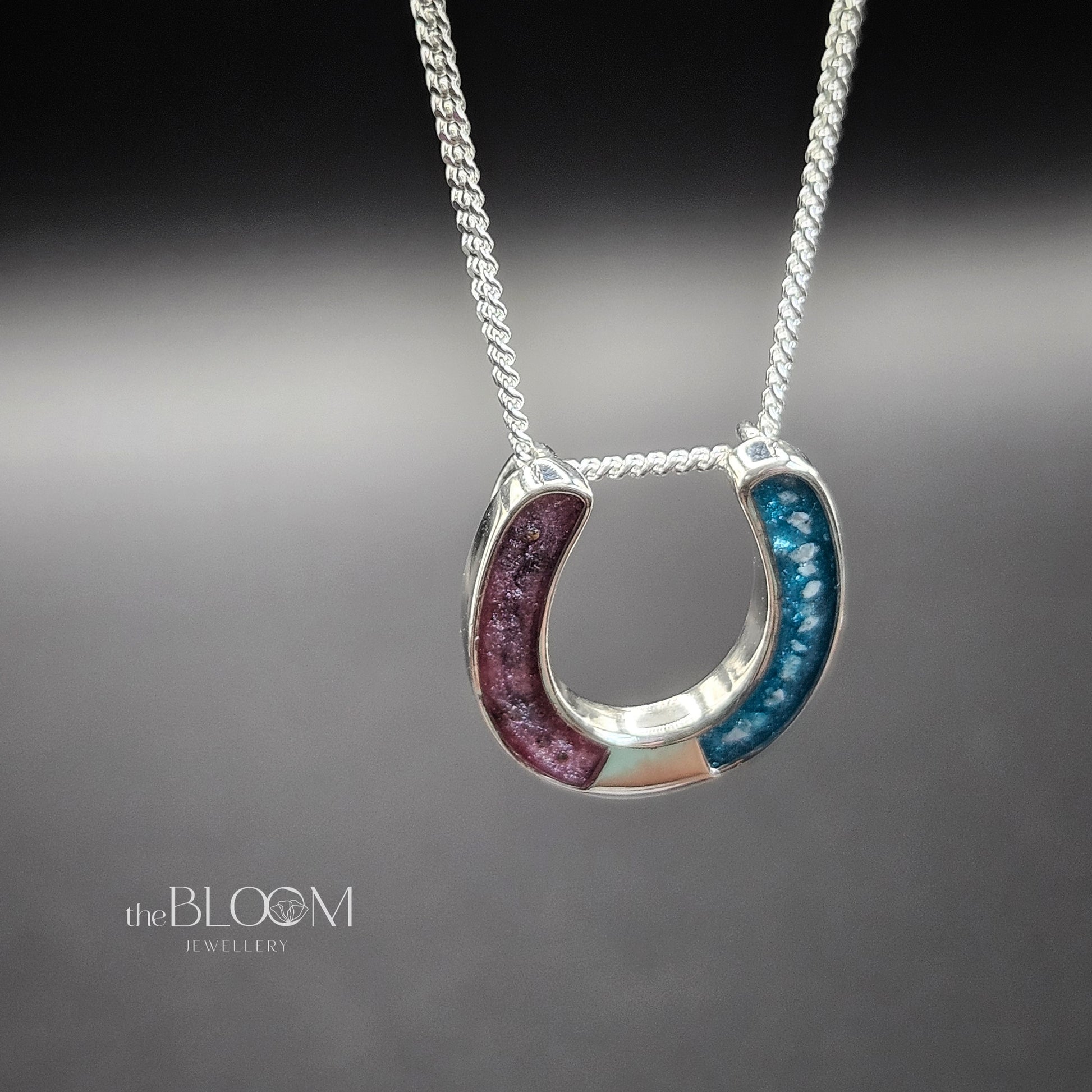 Horseshoe-shaped pendant on a chain against a gray background, keepsake jewellery