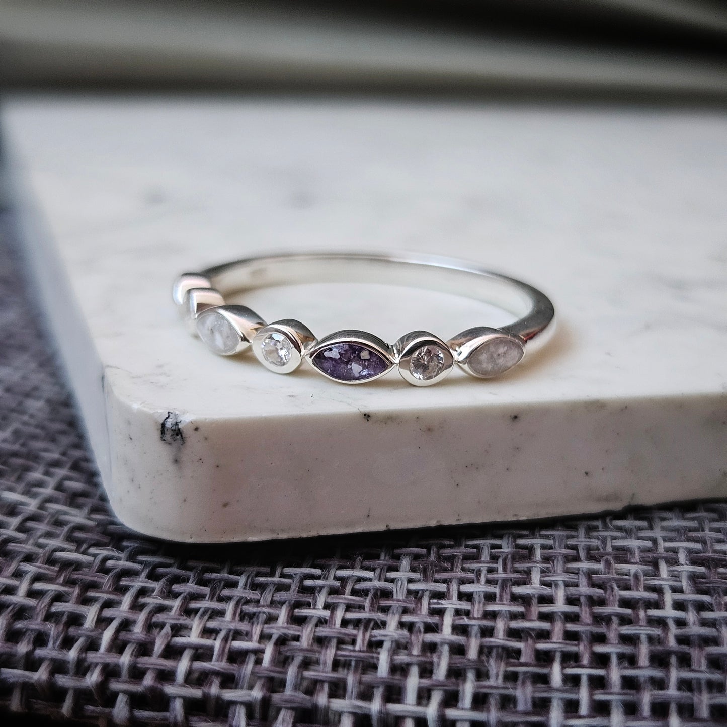 Silver ring with a purple gemstone on a textured surface