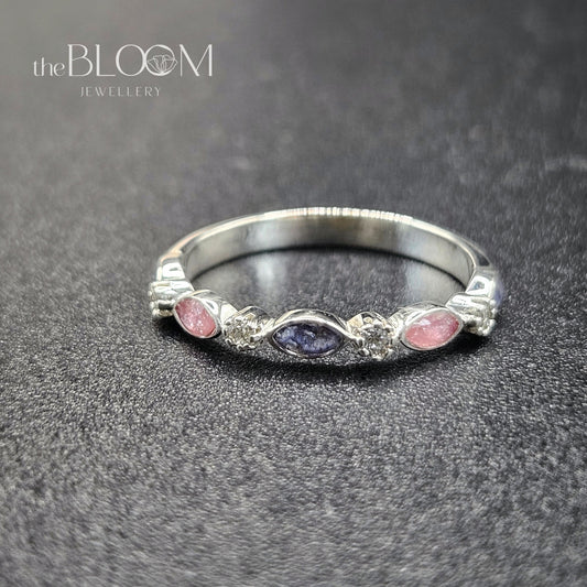 Silver ring with pink and purple stones on a dark textured surface, branded 'the BLOOM JEWELLERY'.