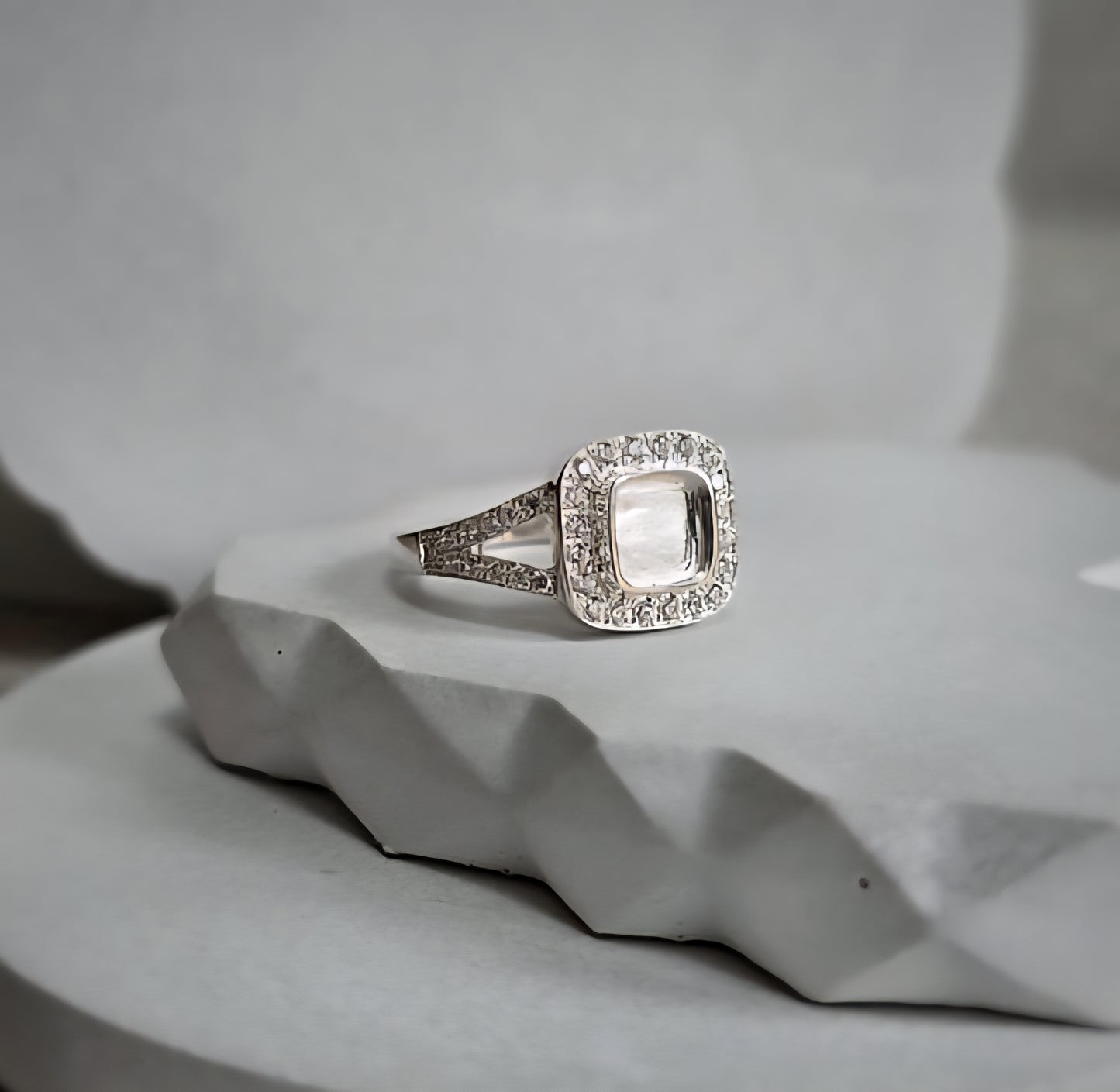 Silver ring with a diamond accent on a textured gray surface