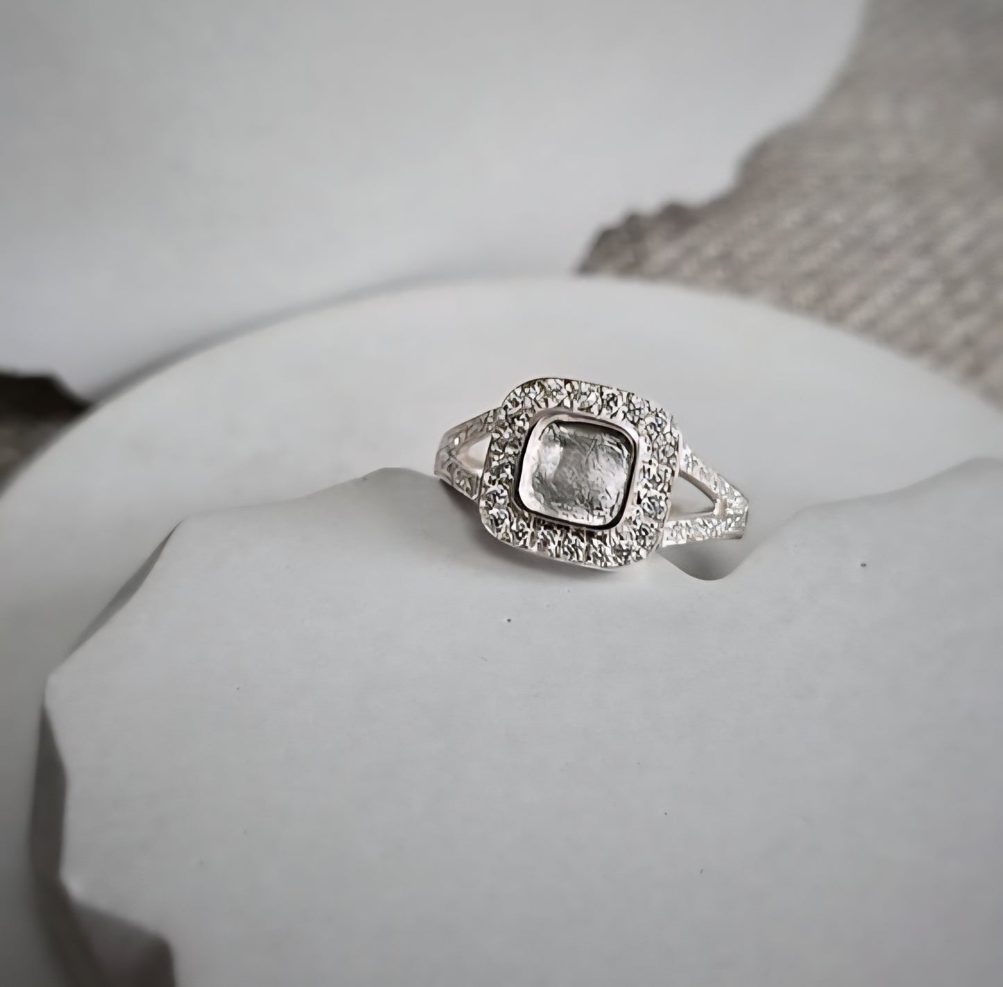 Silver ring with a clear gemstone on a white surface