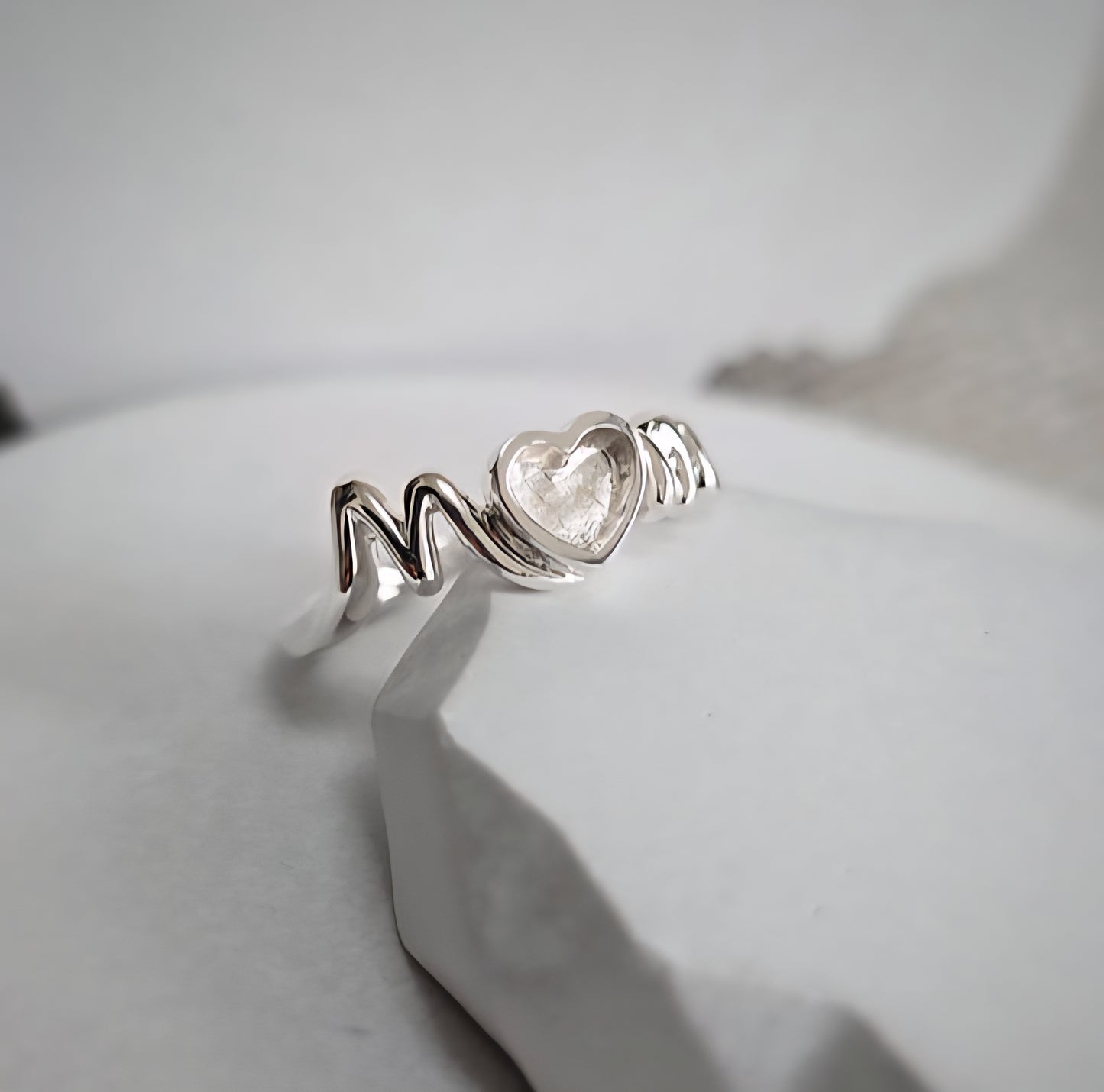 Silver ring with heart-shaped gemstone on a light gray background
