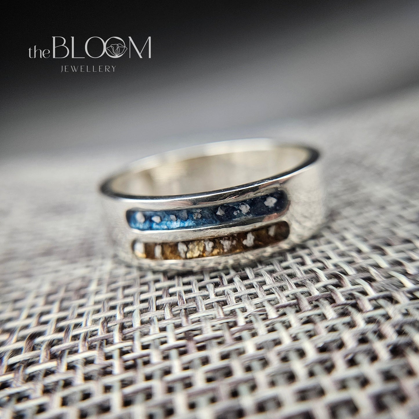 Silver ring with embedded stones on a textured surface, branded 'the BLOOM JEWELLERY'.