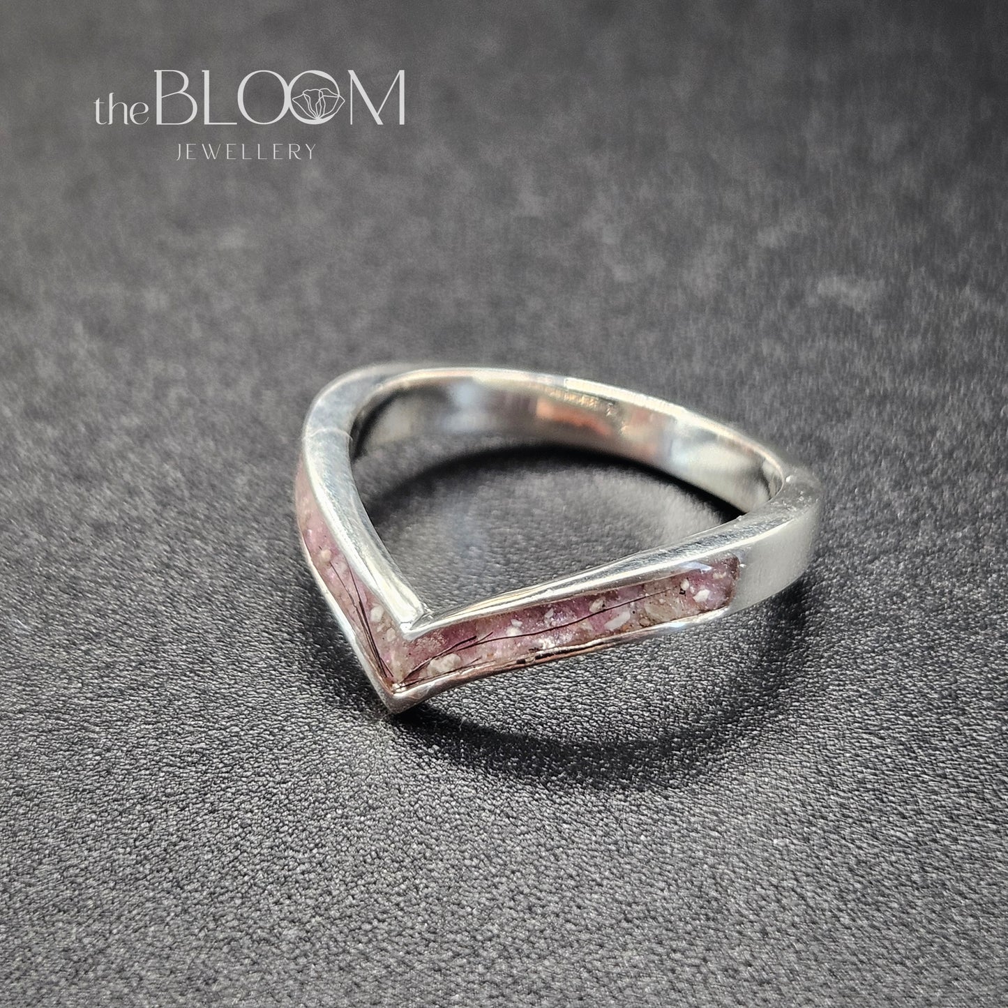 Silver ring with pink interior on a gray surface, branded 'the BLOOM Jewellery'.