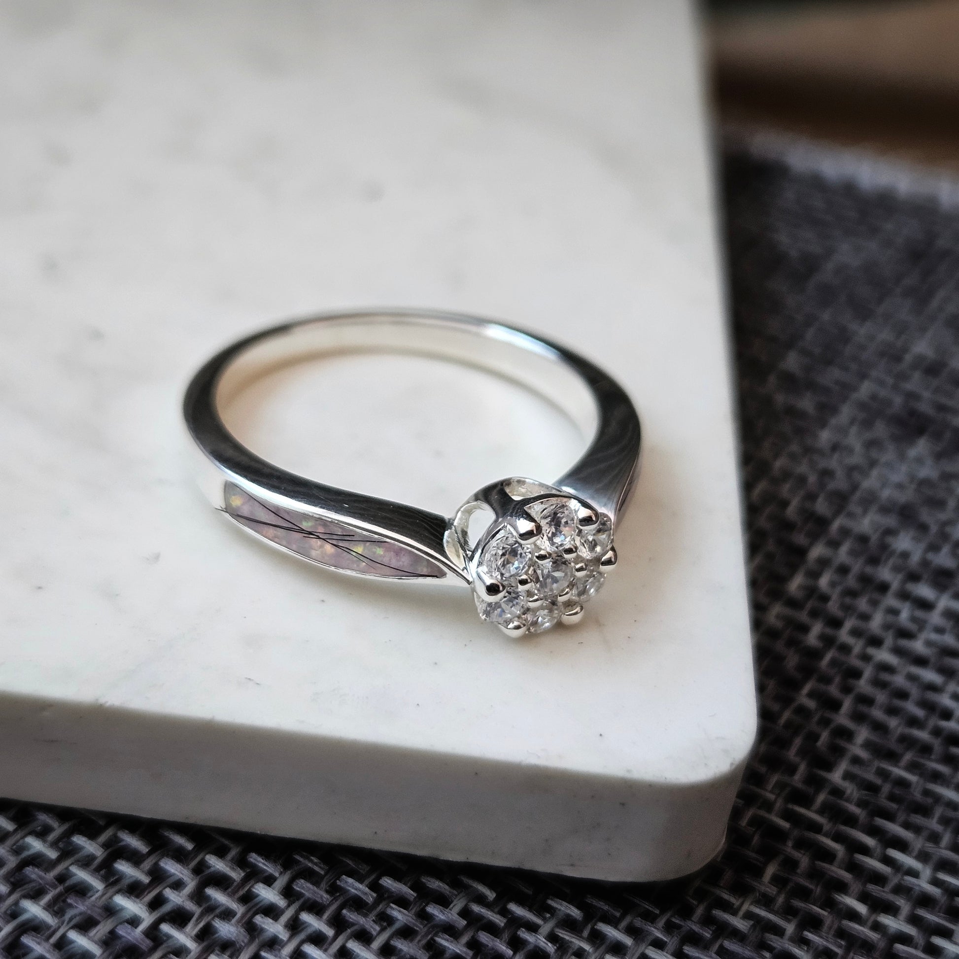 Silver ring with a diamond on a marble surface