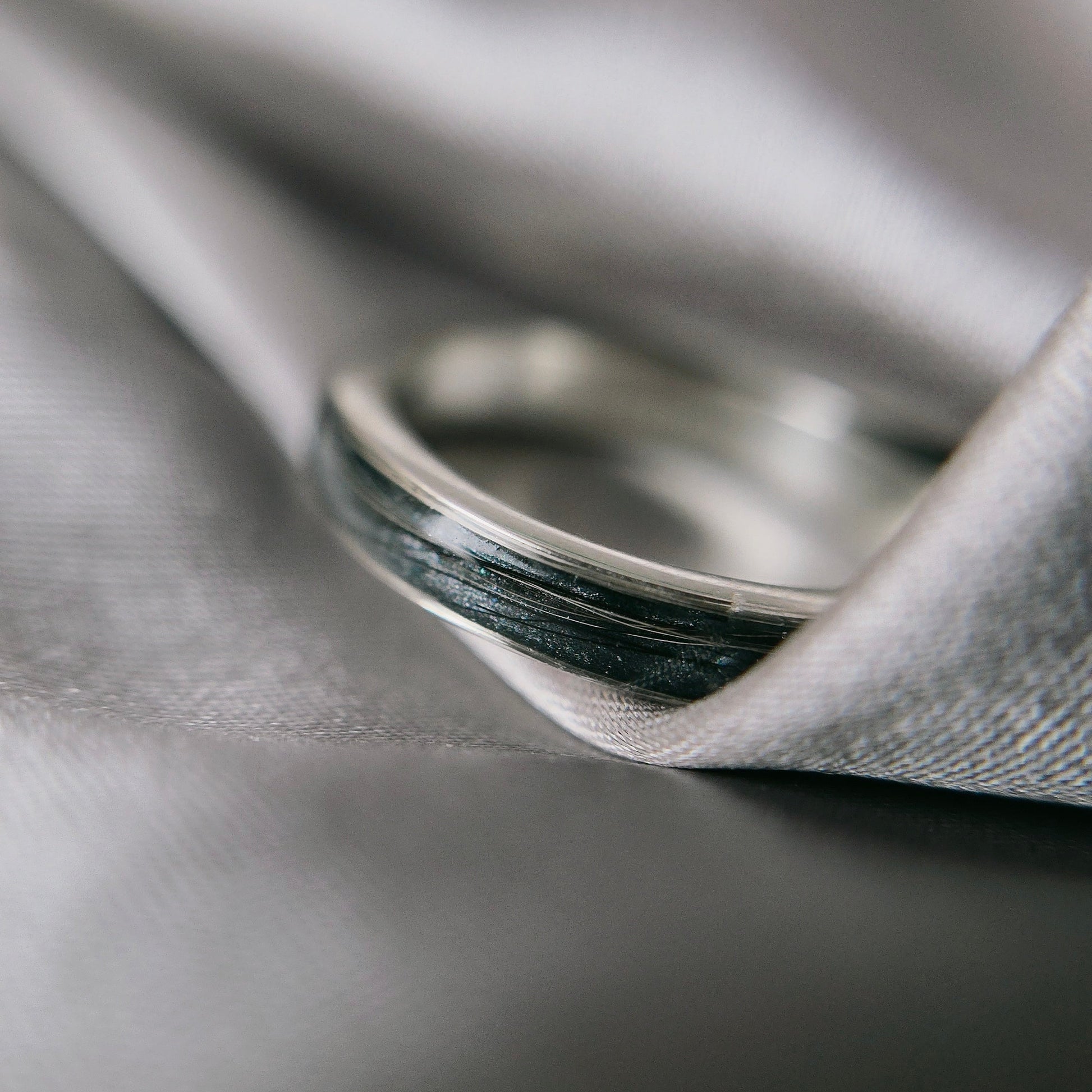 Silver ring on a gray fabric surface