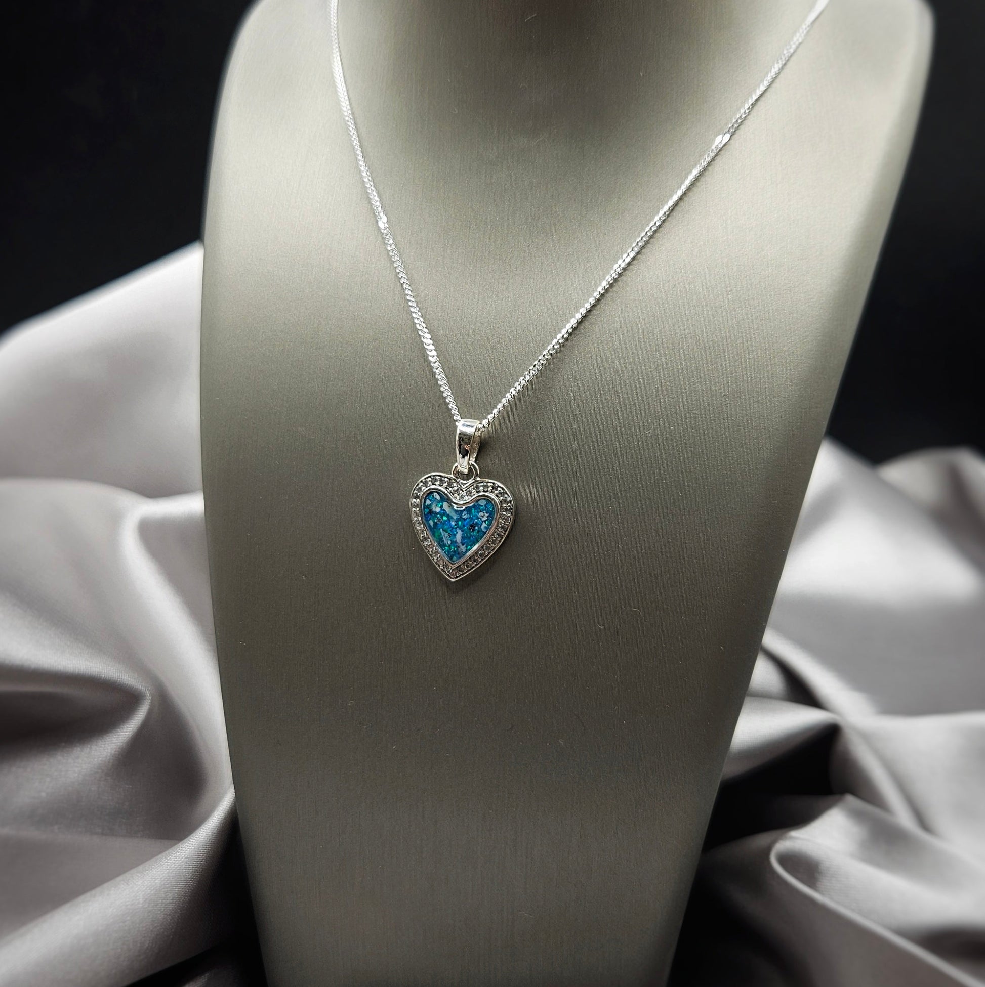 Necklace with a heart-shaped blue pendant on a mannequin bust against a dark background