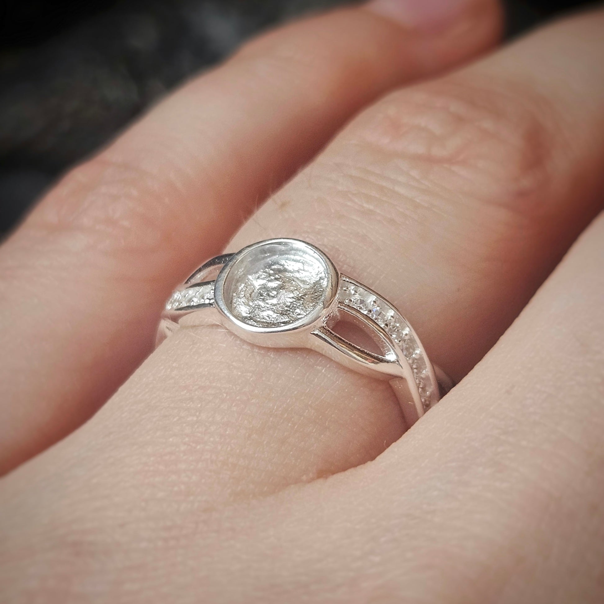 Silver ring with ashes on a person's finger