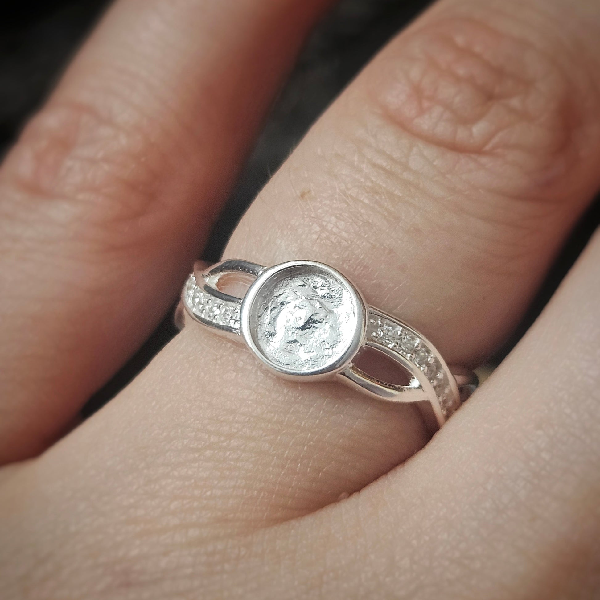 Silver ring with ashes on a finger