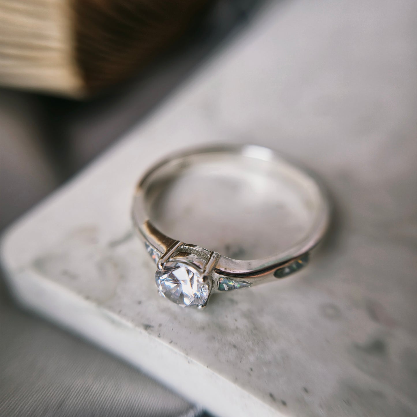 Silver ring with a diamond on a marble surface