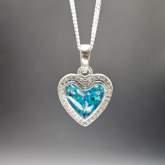 Heart-shaped pendant with blue center and silver frame on a gray background