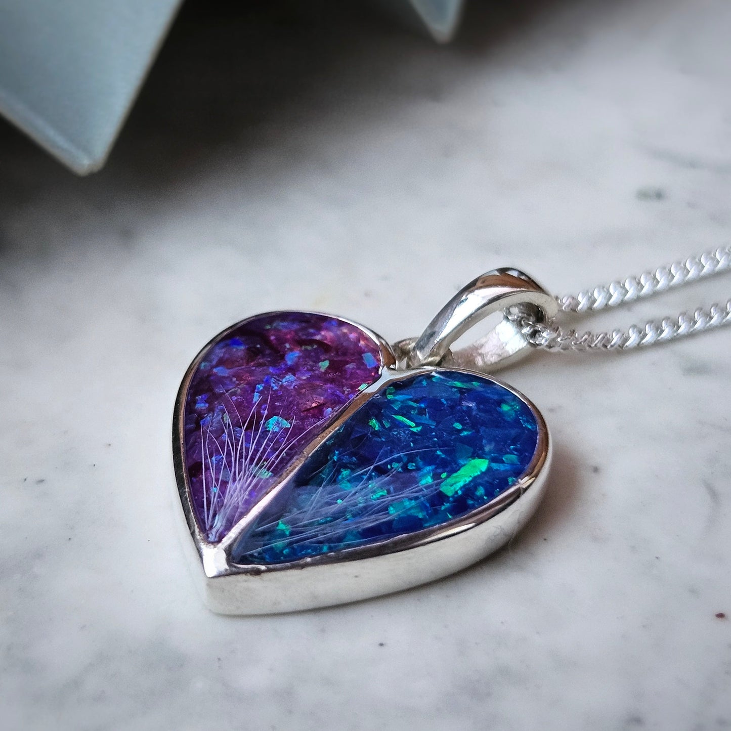 Heart-shaped pendant with purple and blue iridescent finish on a marble surface
