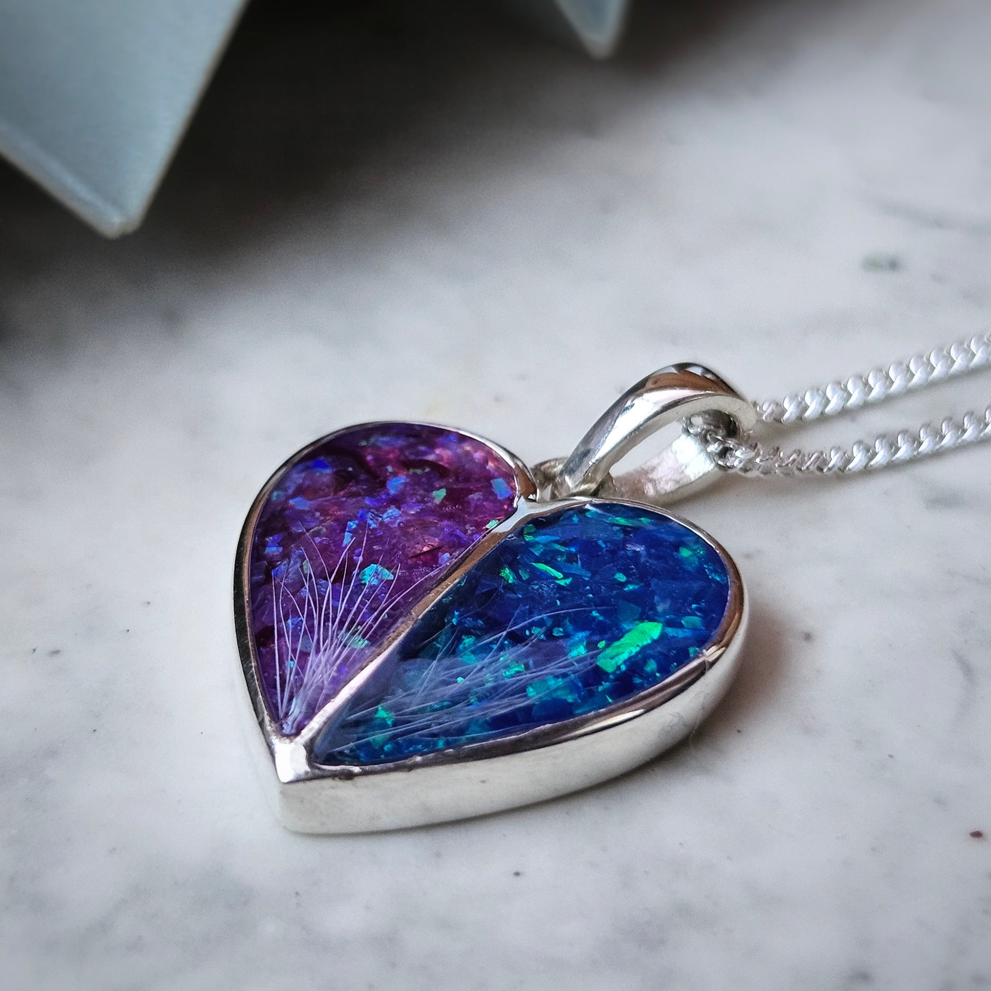 Heart-shaped pendant with purple and blue iridescent finish on a marble surface