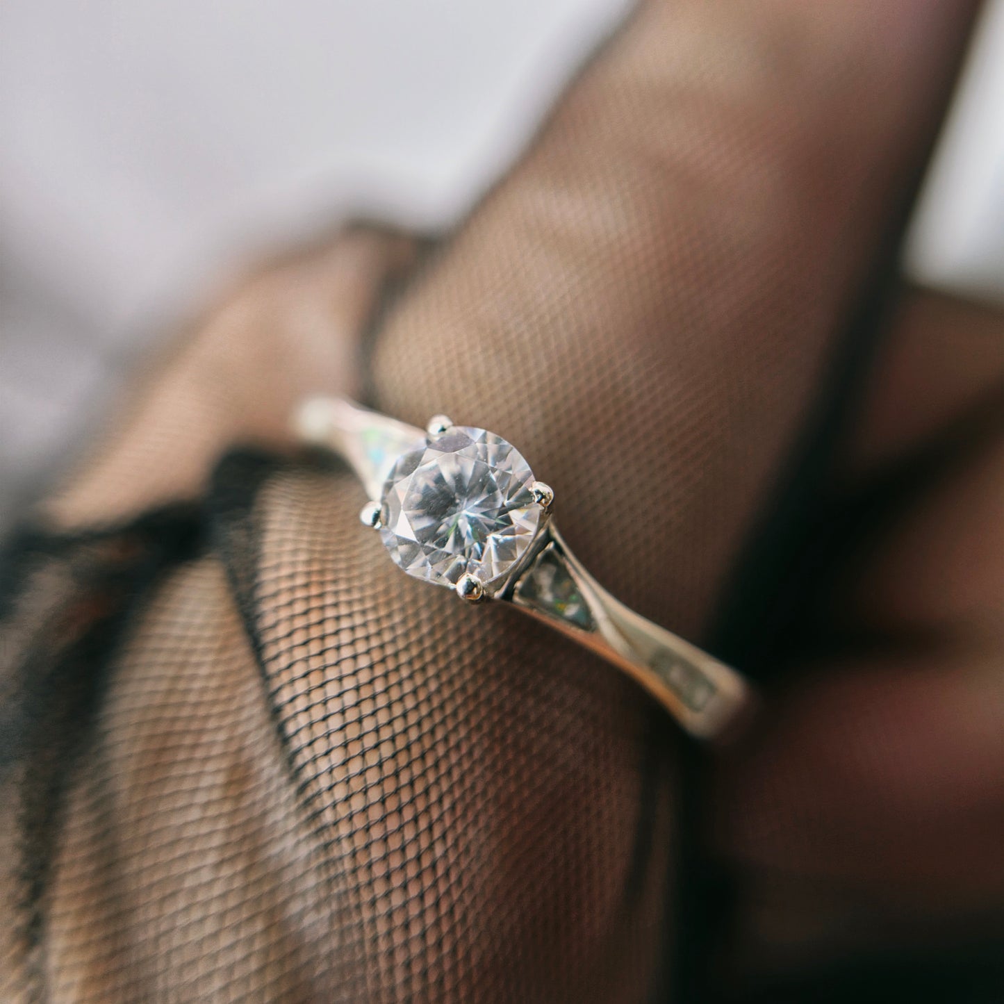 Diamond ring on a finger with a blurred background