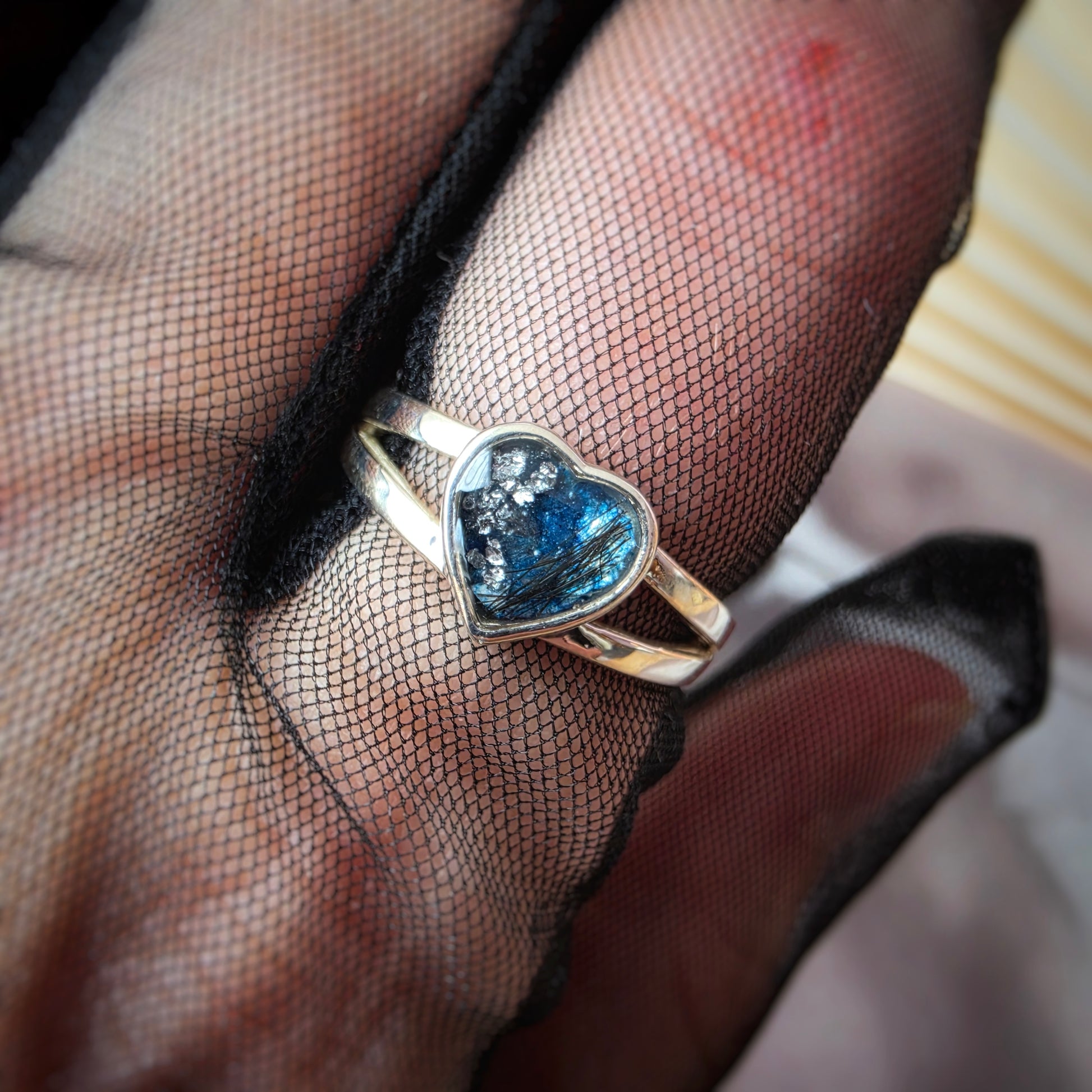  ring with a blue gemstone on a hand wearing black mesh glove