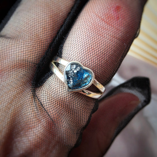  ring with a blue gemstone on a hand wearing black mesh glove