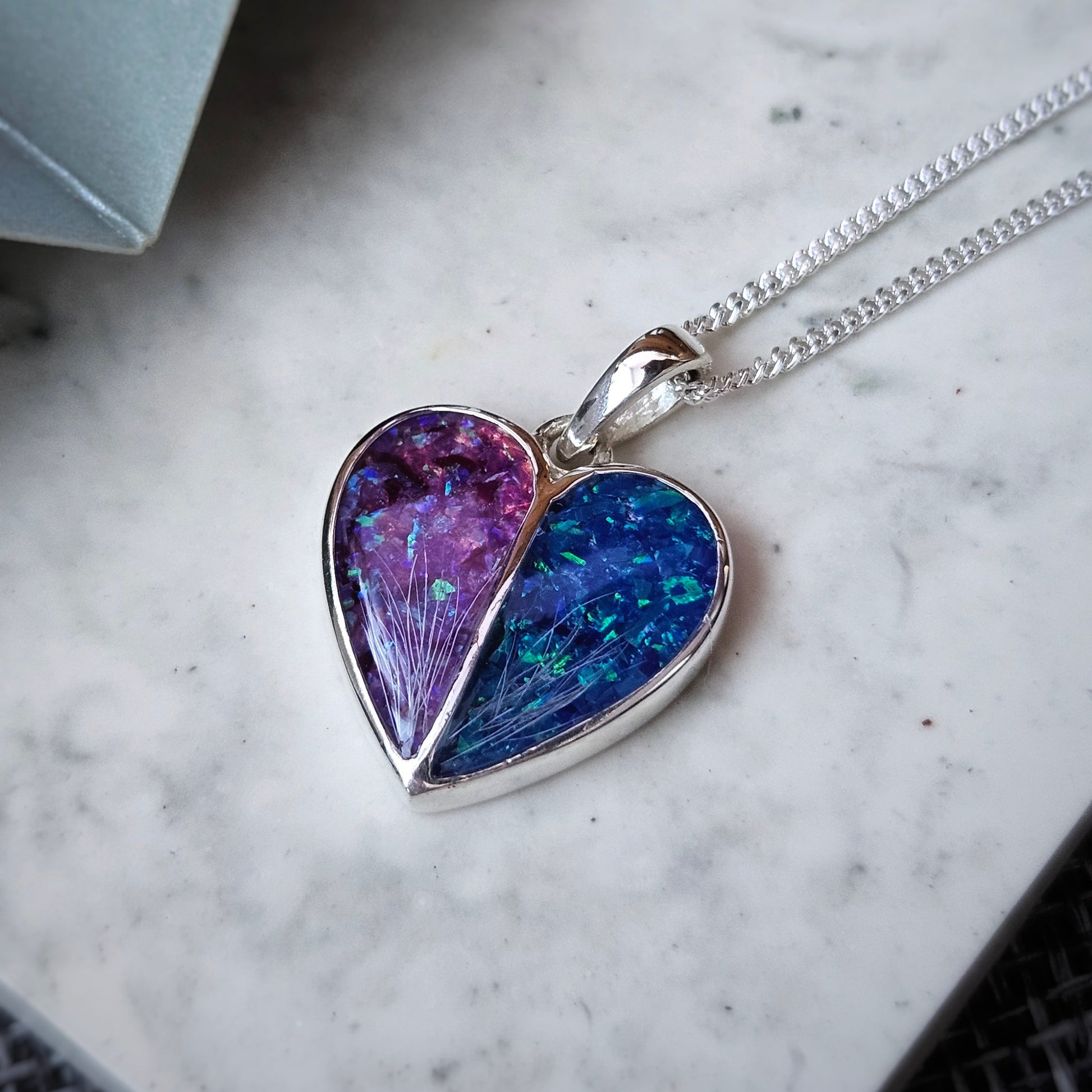 Heart-shaped pendant with a colorful interior on a marble surface