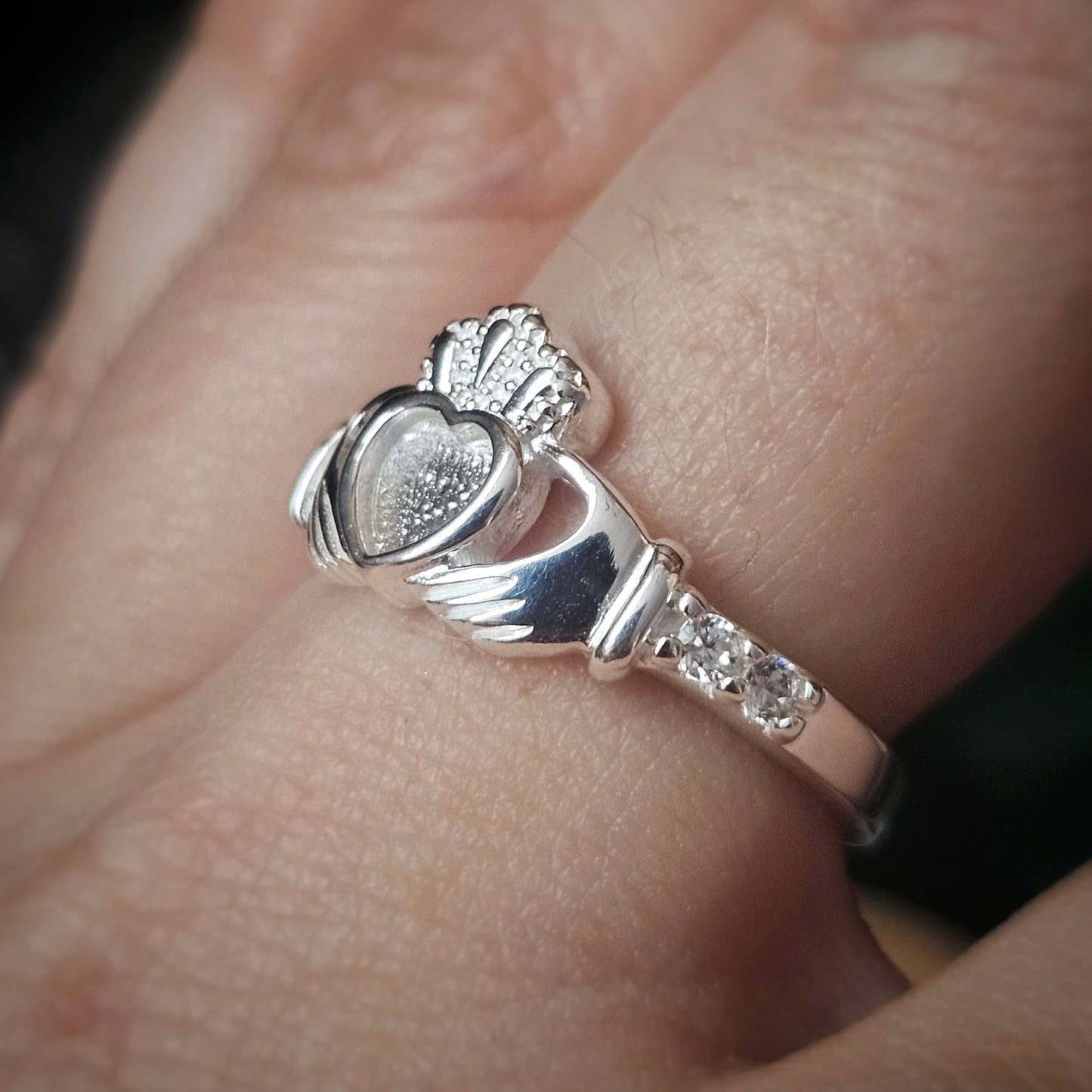 Silver Claddagh ring on a person's finger with a blurred background