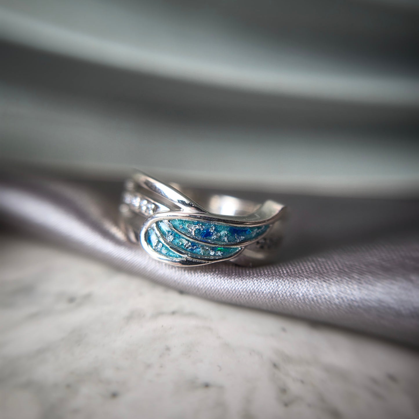 Silver ring with blue accents on a textured fabric background