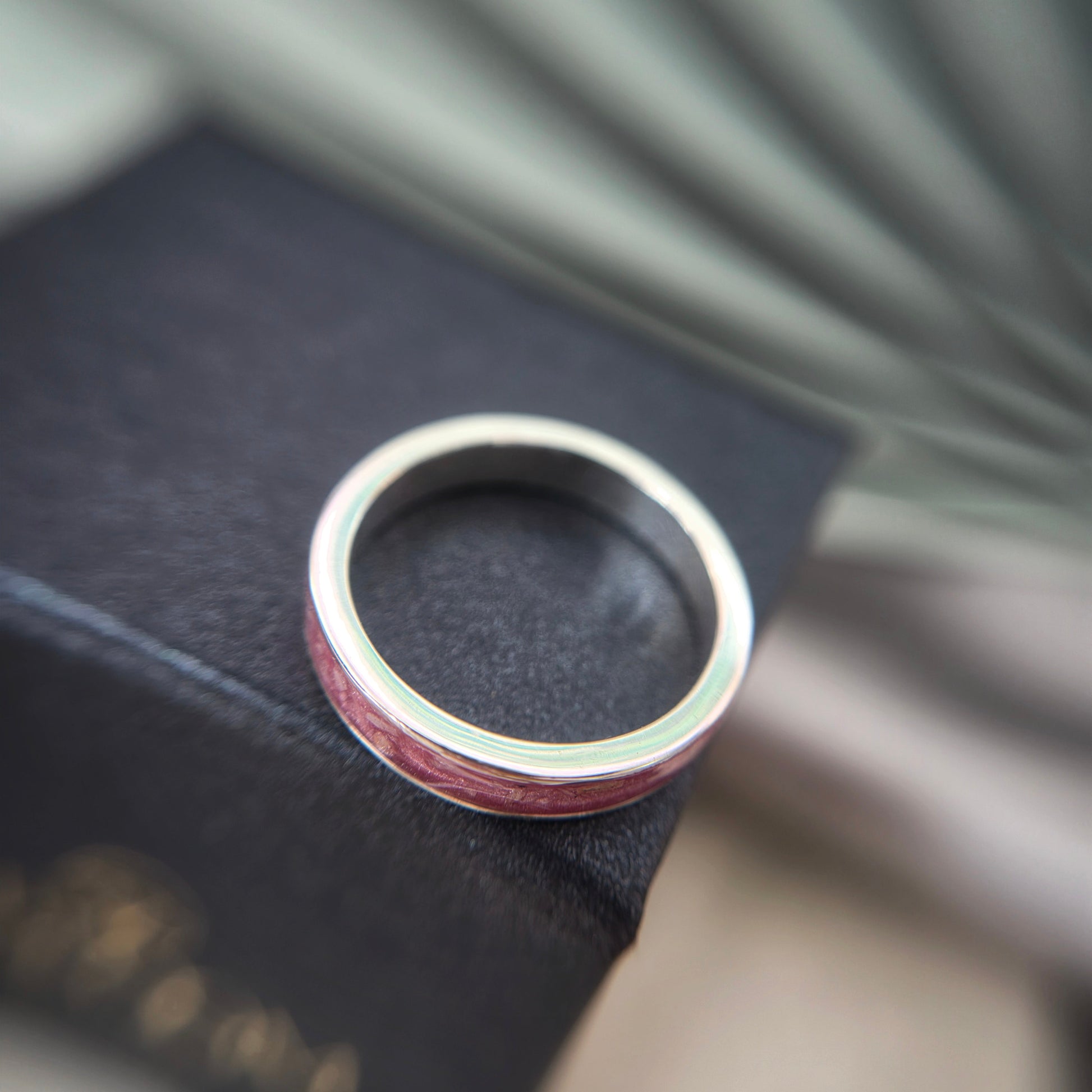 Silver ring with a red interior on a dark surface