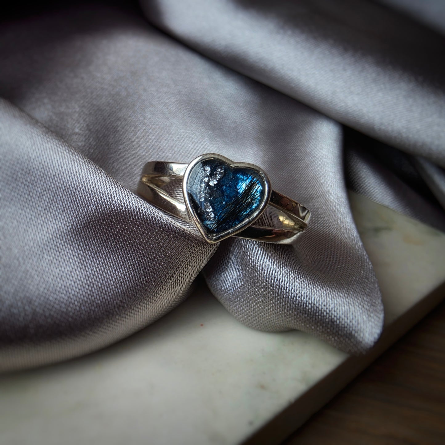 Silver ring with a blue gemstone on a gray fabric background