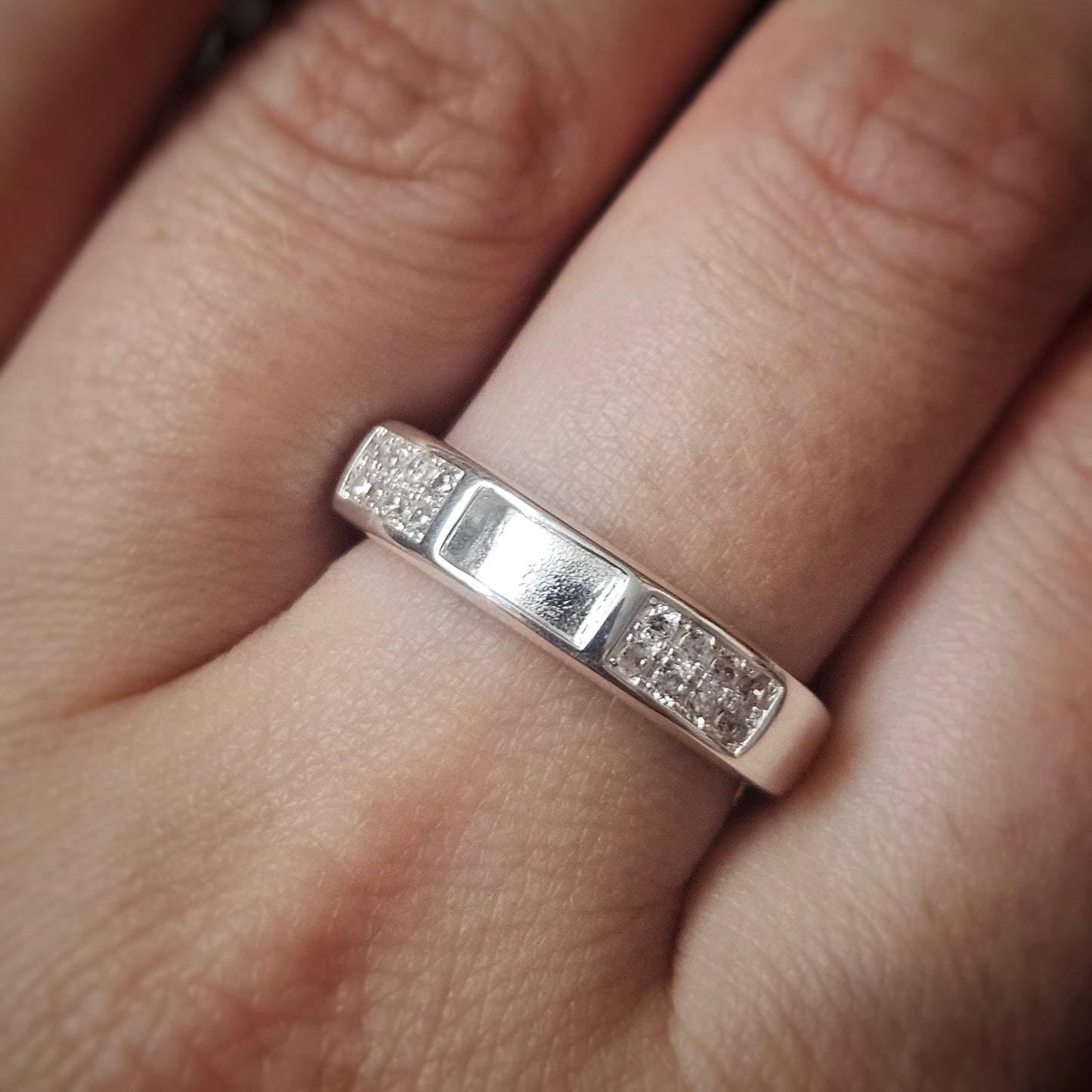 Silver ring with small diamonds on a finger