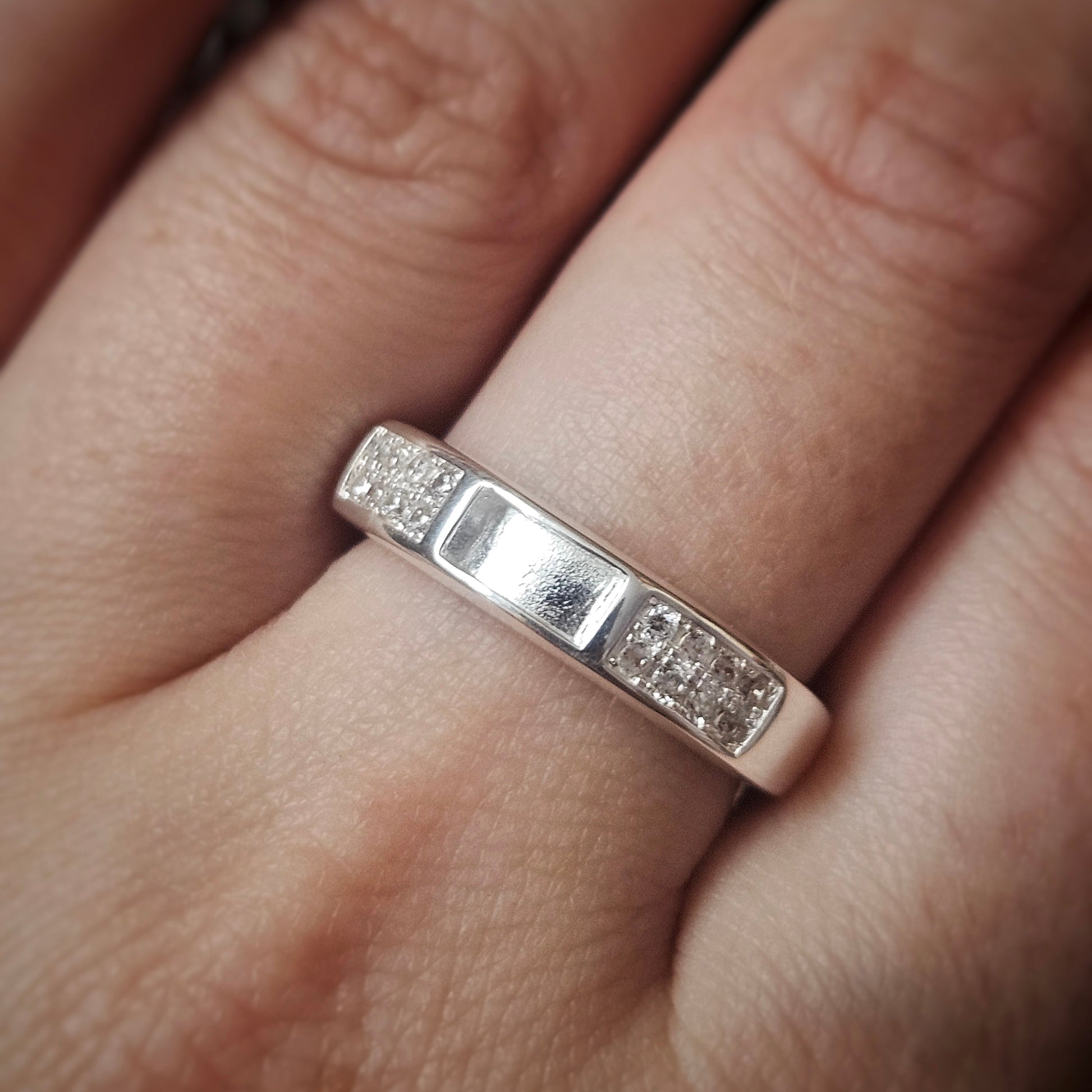 Silver ring with small diamonds on a finger