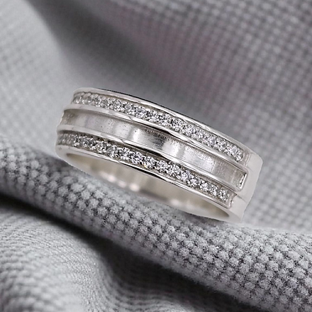 Silver ring with diamond accents on a gray fabric background