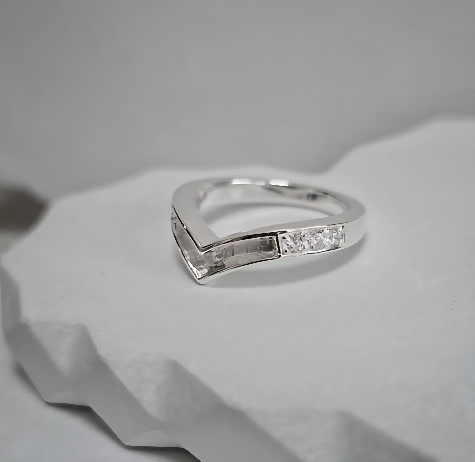 Silver ring with small diamonds on a light gray background