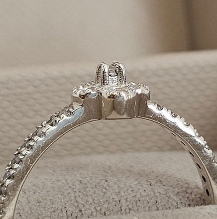 Silver ring with a diamond on a beige surface