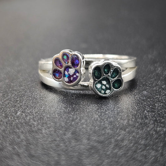 Silver ring with paw print designs on a dark gray background