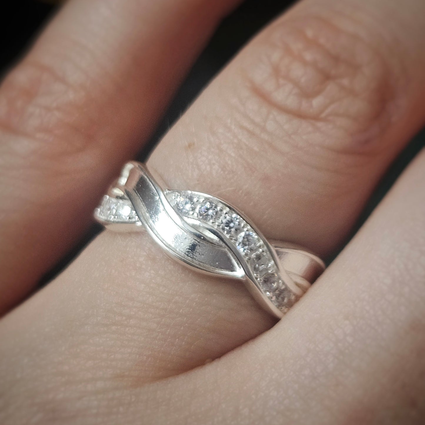 Silver ring with small diamonds on a finger
