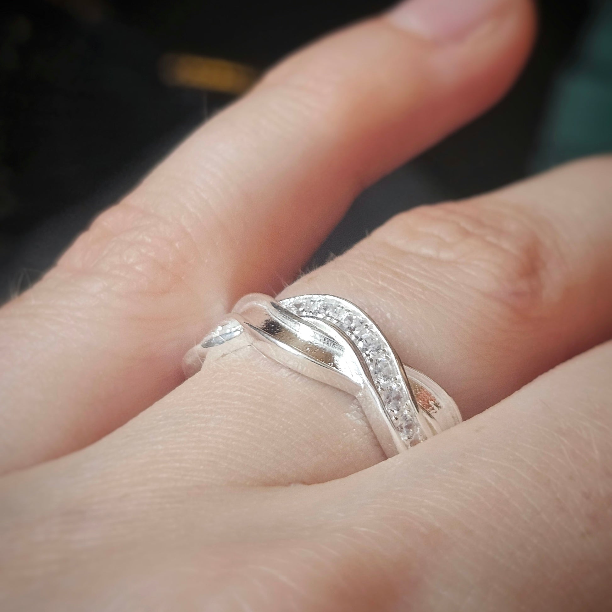 Close-up of a hand wearing silver keepsake ring with a blurred background