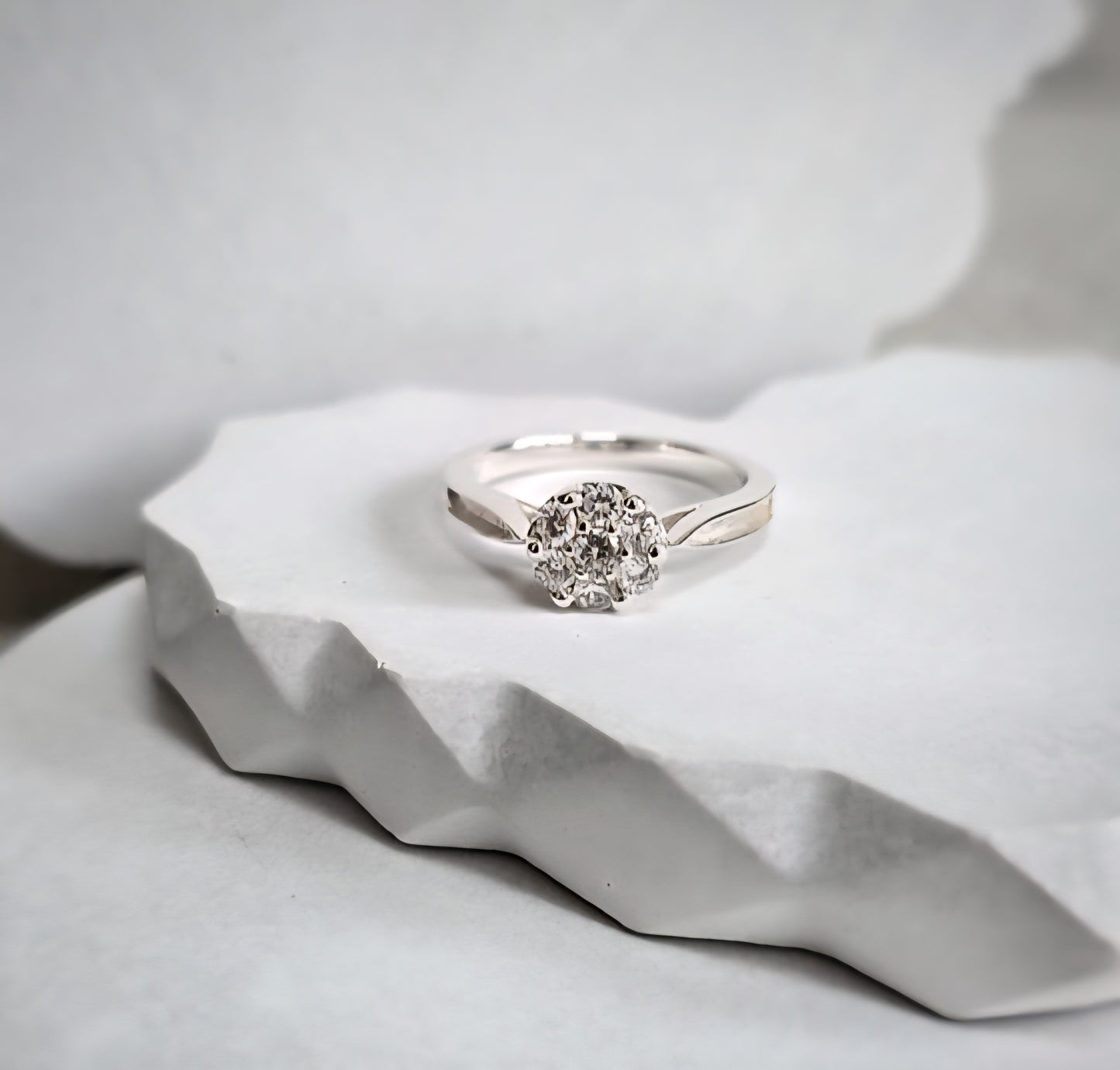 Silver ring with a diamond shaped cz on a white stone surface