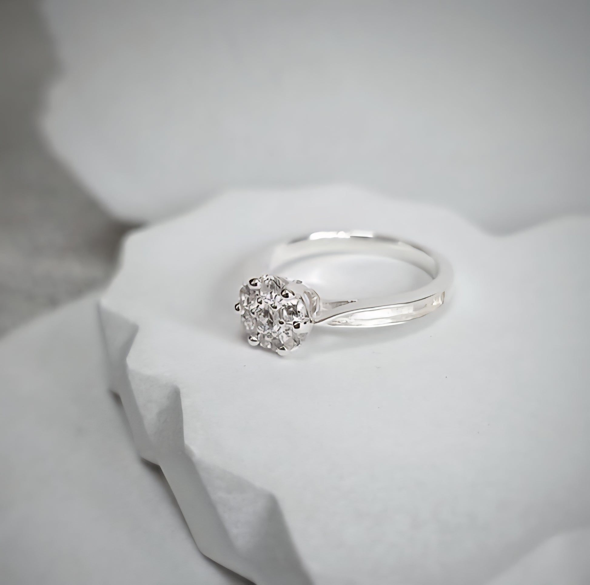 Silver ring with a round-shaped cz on a white stone surface