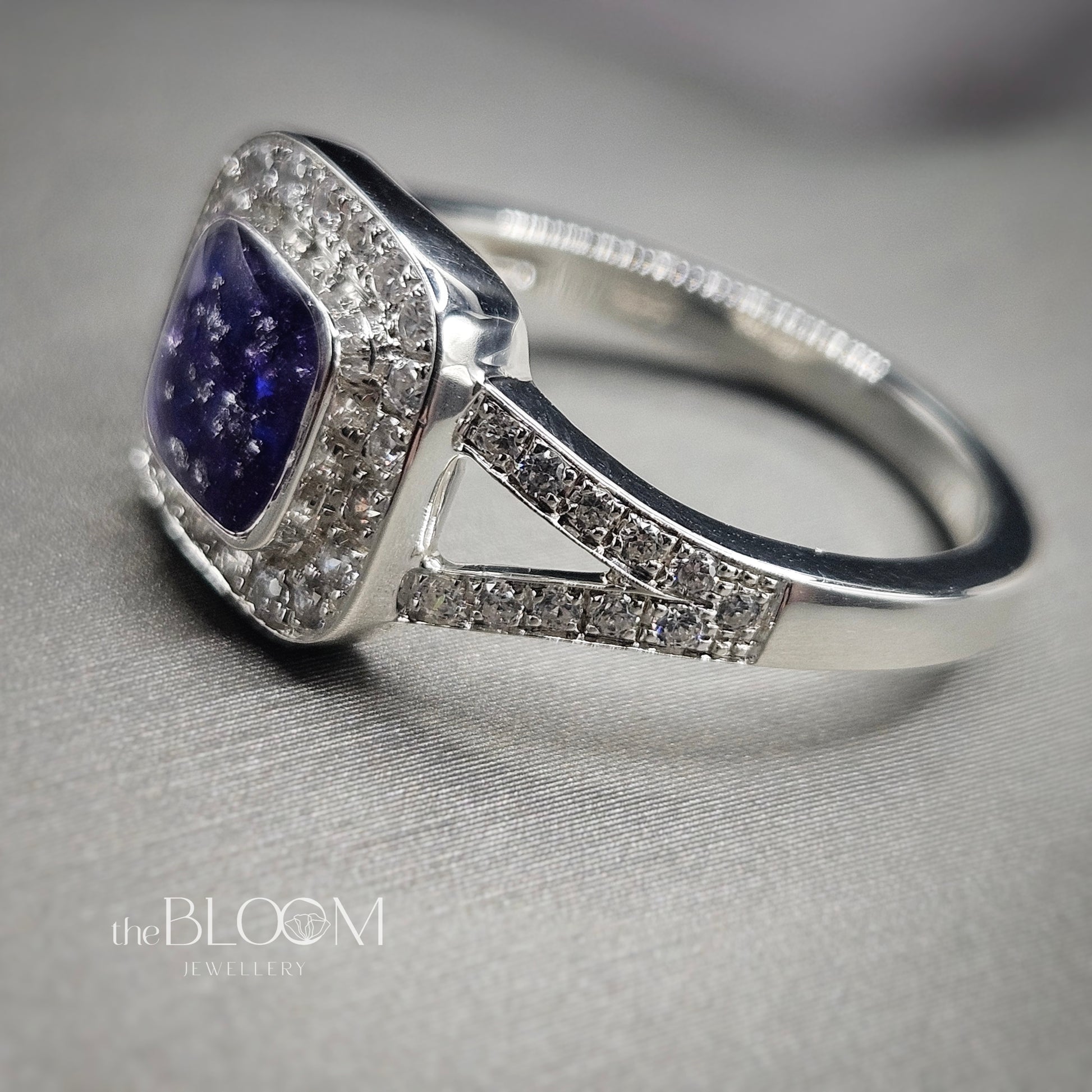 Silver ring with a purple gemstone on a gray background, branded 'the BLOOM JEWELRY'.