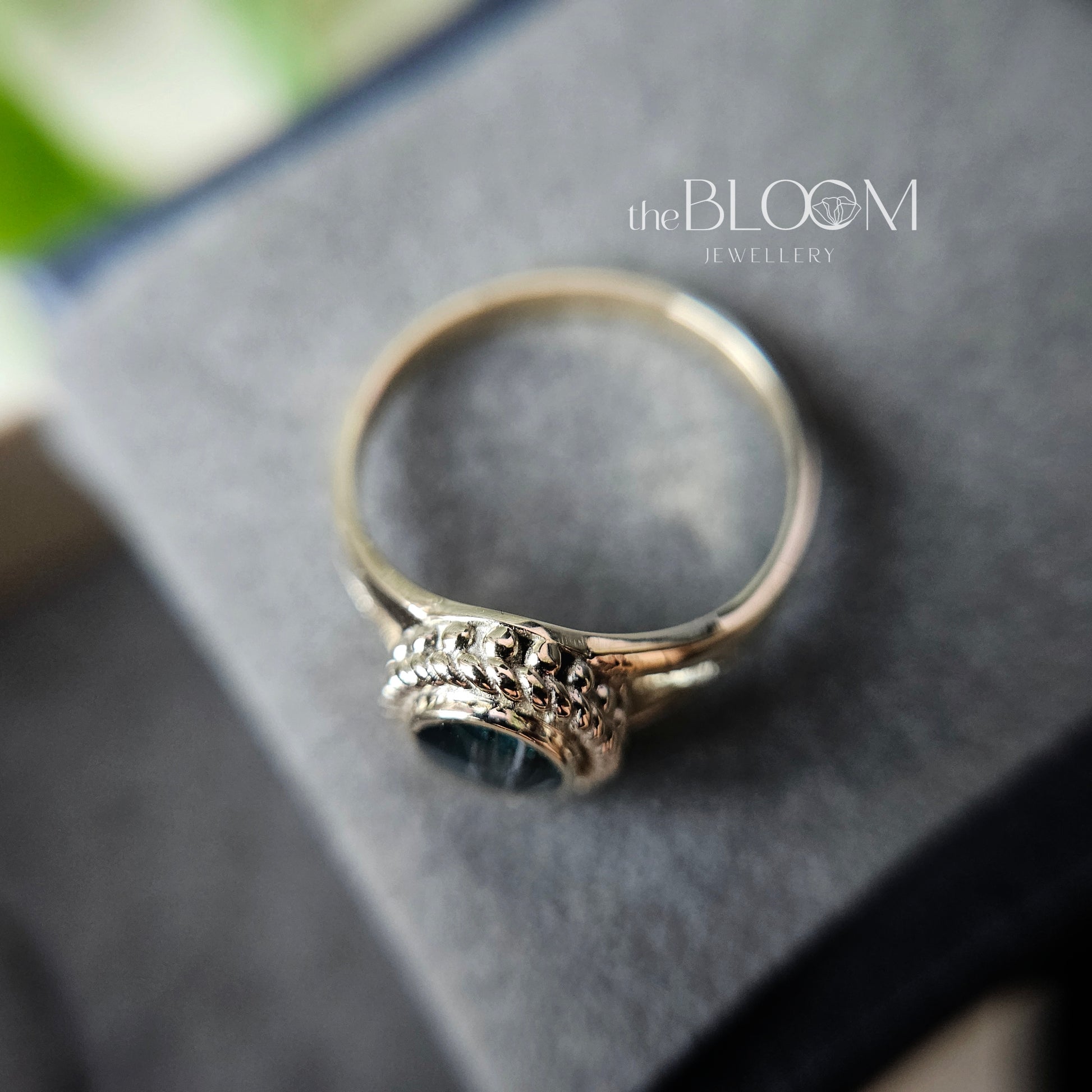 Silver ring on a dark surface with 'the BLOOM Jewellery' branding.
