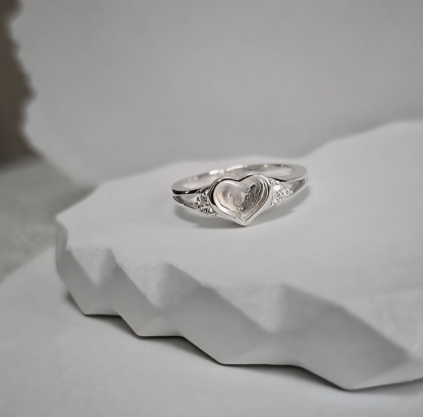 Silver ring with a heart-shaped design on a light gray background