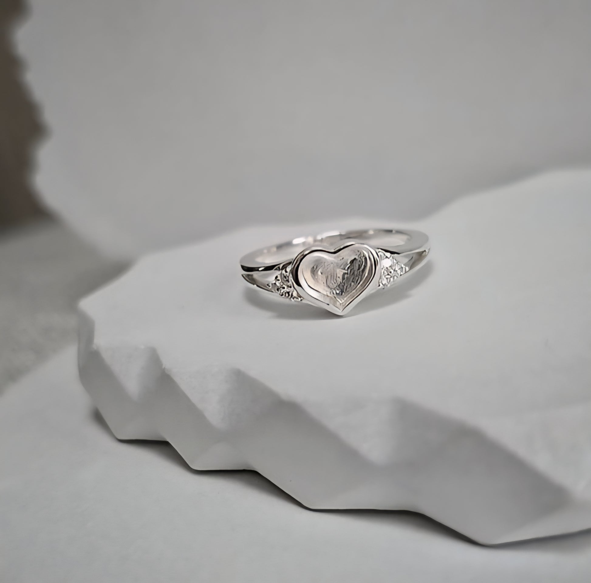 Silver ring with a heart-shaped design on a light gray background