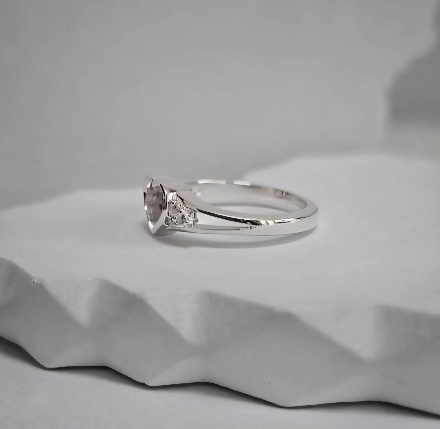 Silver ring with a diamond on a gray textured surface