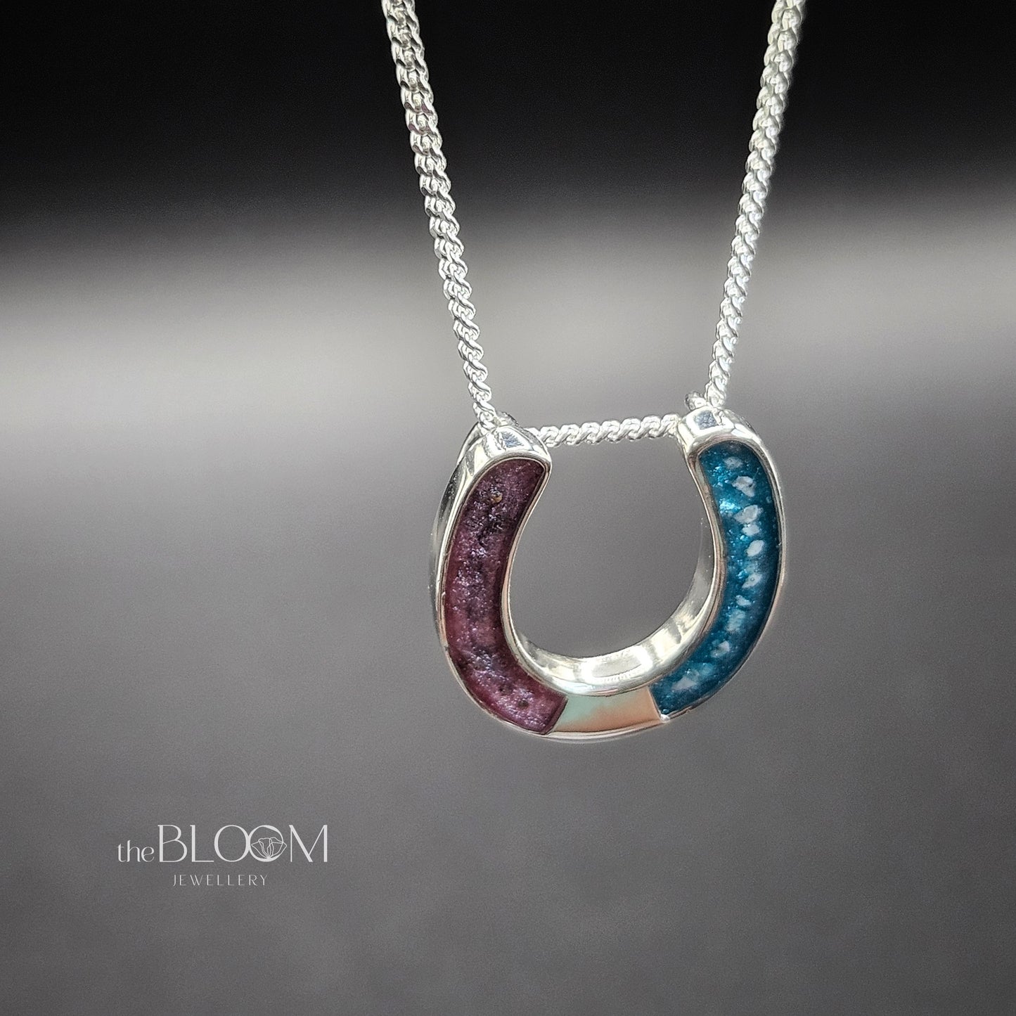 Horseshoe-shaped pendant on a chain against a gray background, keepsake jewellery